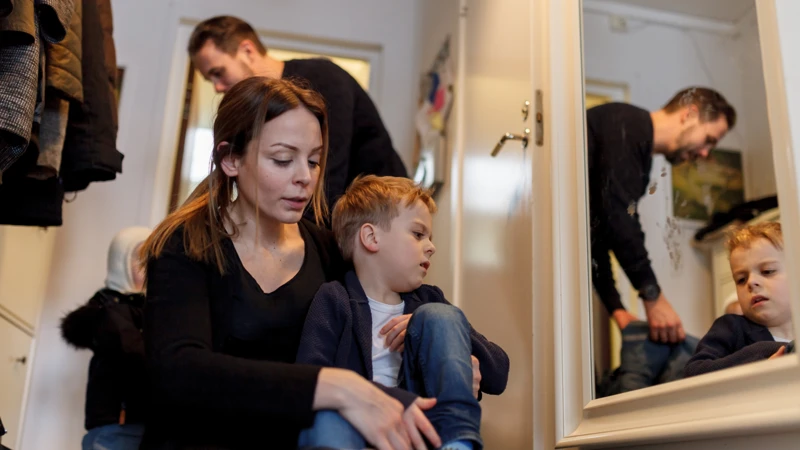 En kvinna sitter bredvid en pojke framför en spegel.
