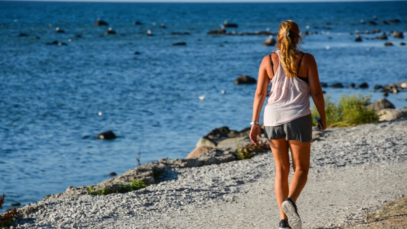 Ung kvinna går längs stenstrand
