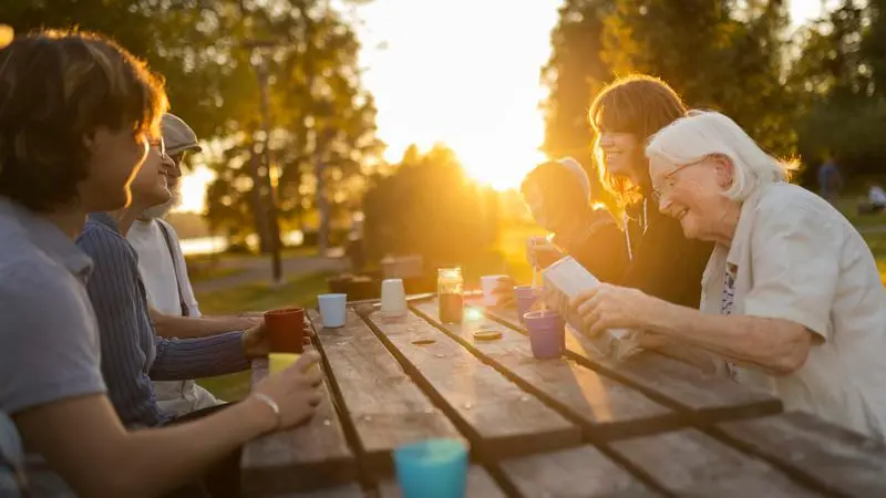Personer som fikar vid ett bord i solen