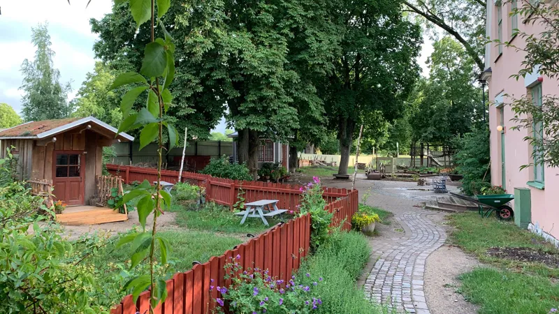 Ett trädgårdsområde med ett rött staket och ett träskjul.