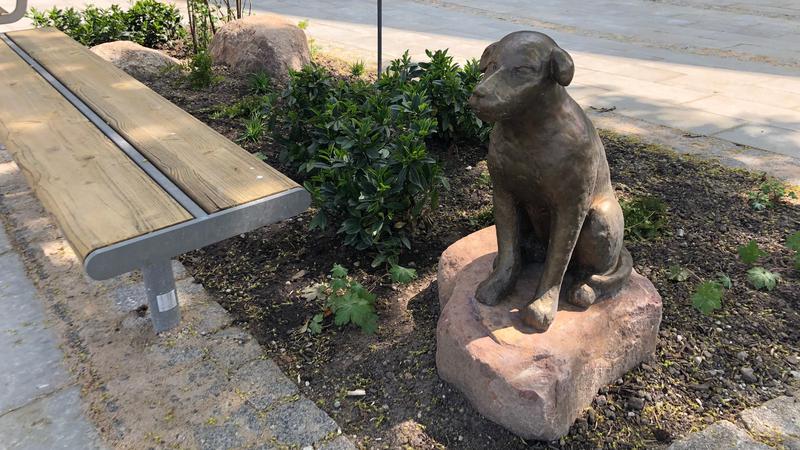 En skulptur av en hund i brons, sittande på en sten
