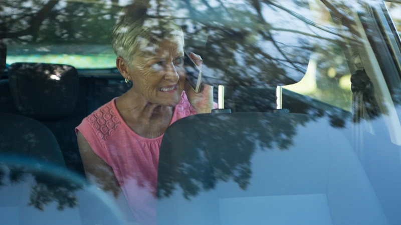 En kvinna som sitter i en bil och pratar i mobiltelefon.