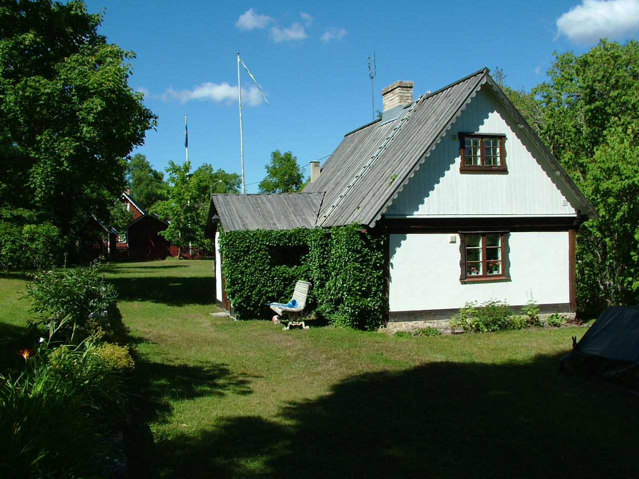 Ett vitt hus med ett trätak, bruna fönster och en brun ytterdörr.