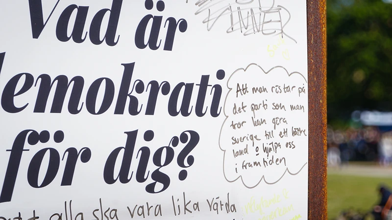 En skylt om demokrati som står vid sidan av en väg.