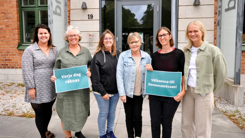 En grupp människor som håller upp skyltar framför en byggnad.