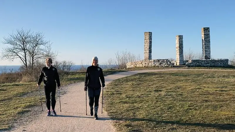 två personer går stavgång på galgberget en kall men solig dag