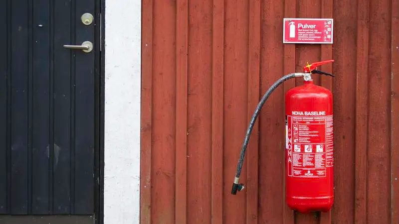 En brandsläckare fäst på en röd vägg
