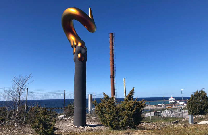 En pelar i mörk betong kröns av en metallicfärgad skruv med vass spets