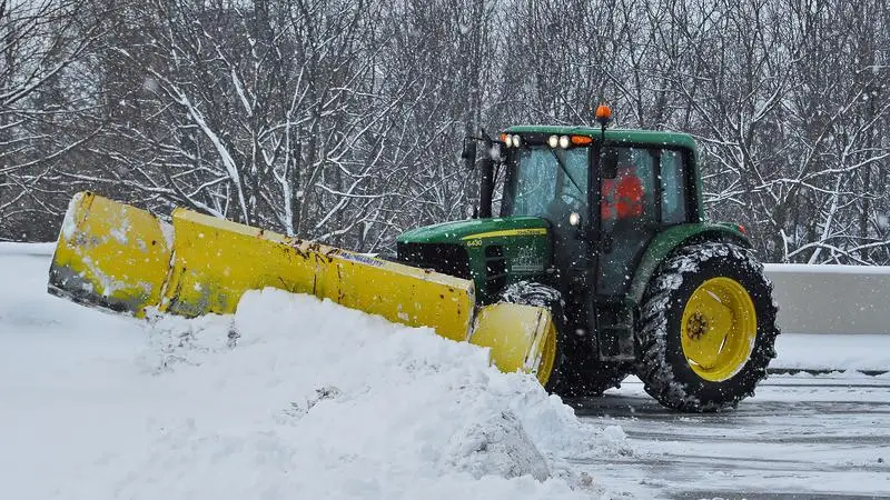 En traktor plogar snö på en parkeringsplats