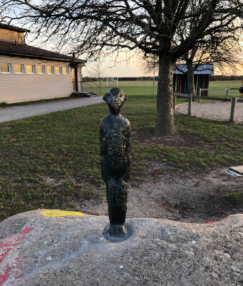 En liten människofigur i metall, figuren ser glad ut