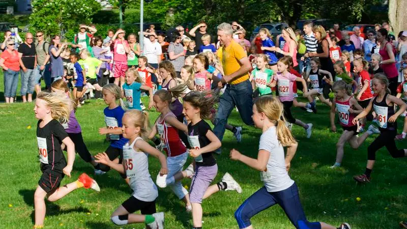 Barn som springer ett lopp på en grön gräsmatta