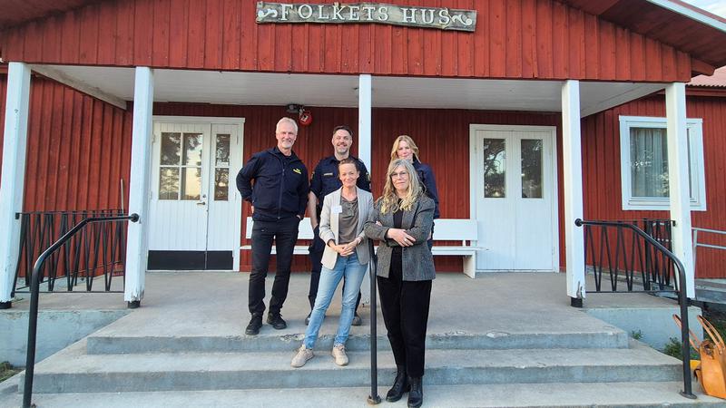 Fem personer på trappan framför ett hus med skylten Folkets hus