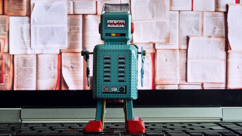 En leksaksrobot som sitter på en bärbar dator.