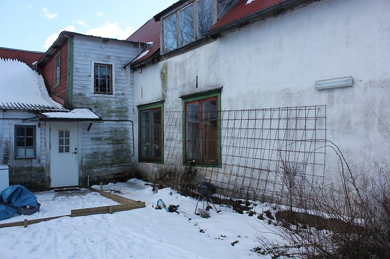Ett vitt hus med en röd ytterdörr, röda fönster och ett rött plåttak.