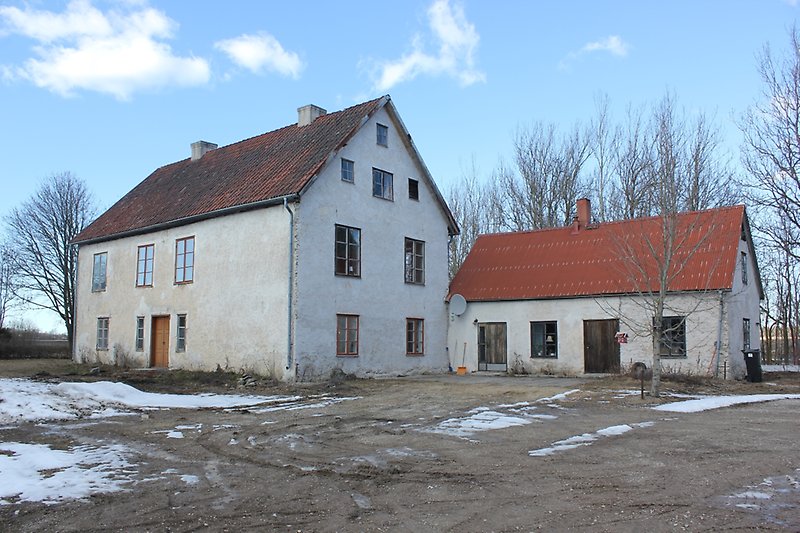 Ett vitt tvåvånings hus med två skorstenar, ett rött tak och ett gårdshus.