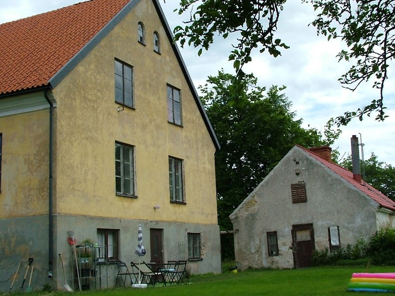 Ett gult hus med bruna dörrar, bruna fönster och ett rött tegeltak.