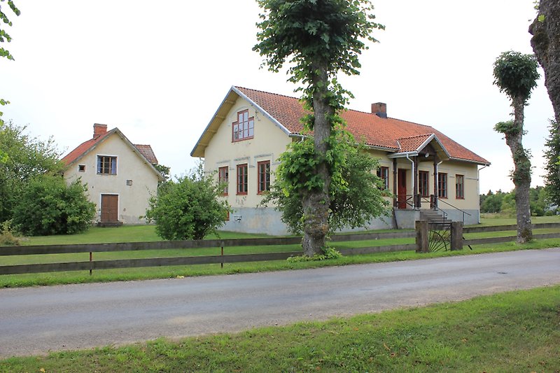 Två ljusgula hus med röda fönster och tak som ligger längs vägen.