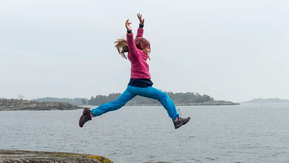 Kvinna i svart jacka och kängor sitter på en stentrappa och ser beslutsam ut.