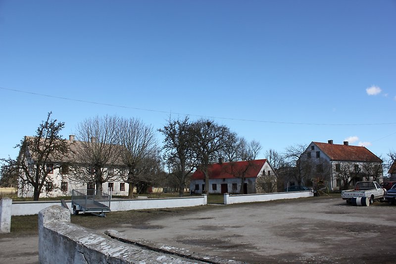 Ett vitt hus med ett grått tak och två vita byggnader med röda tak