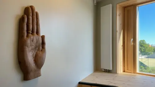 Träkonstverk i form av en handflata på en vägg intill ett fönster