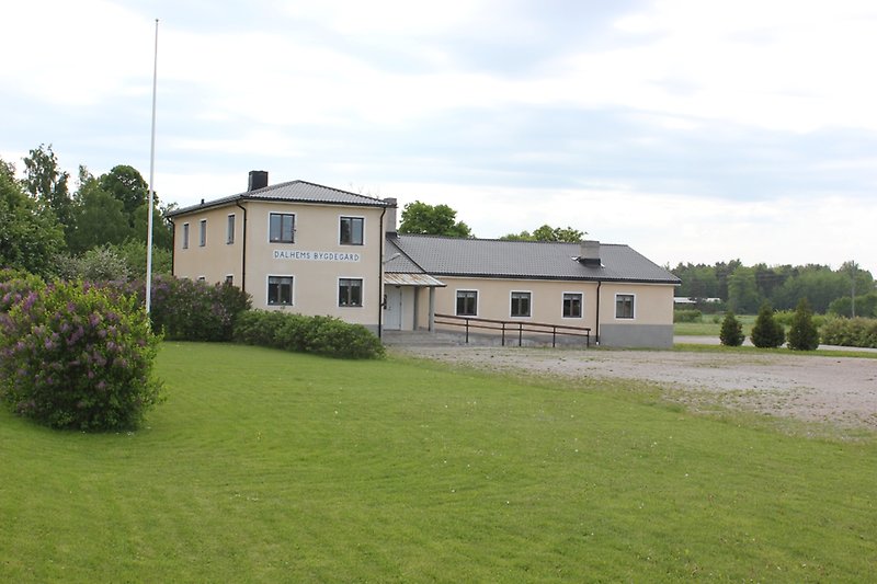 En ljusgul byggnad med svarta fönster och ett svart plåttak.