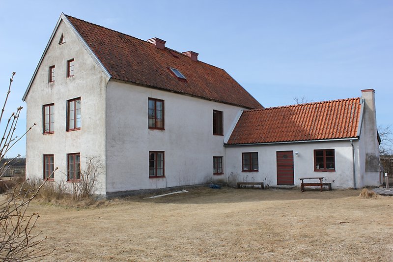 Ett vitt hus med orange tak och liten tillbyggnad