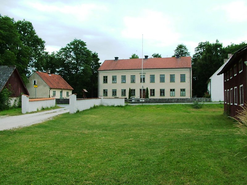 Den största byggnaden i området med gröna fönster och ett rött tak är tingshuset.