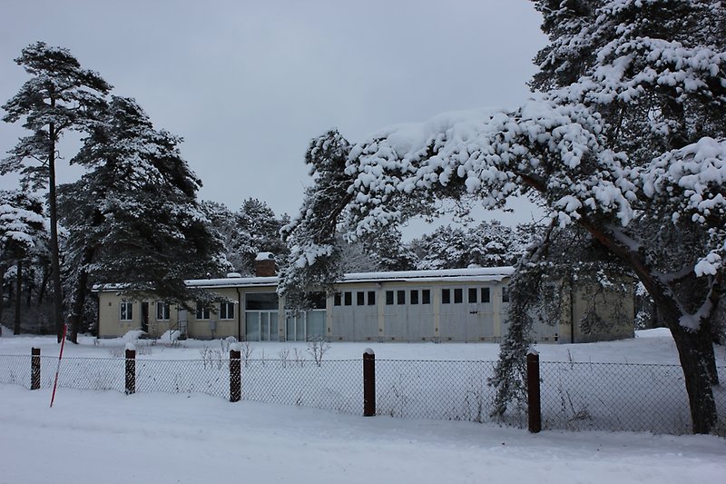 En envåningsbyggnad med fyra stora portar, ljusgula väggar och vita fönster.