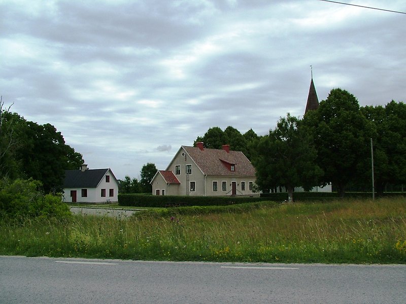 Två hus ligger precis mellan kyrkan och vägen.