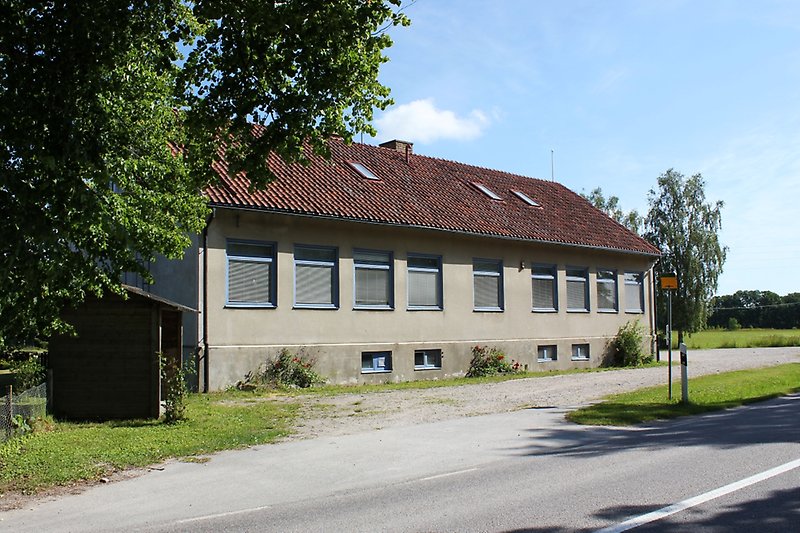 Det finns en busshållplats på baksidan av en grå byggnad.