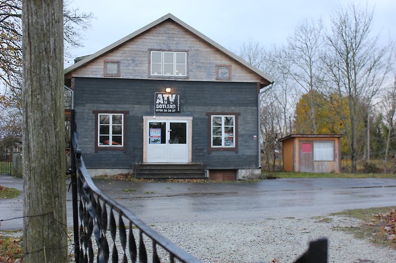 En större blå träbyggnad med vita dörrar och vita fönster.