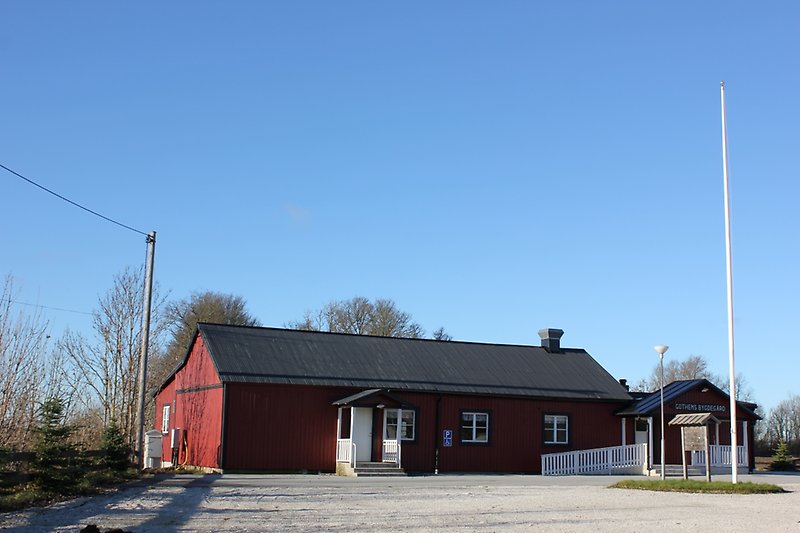 En röd envånings träbyggnad med vita fönster och ett svart plåttak.