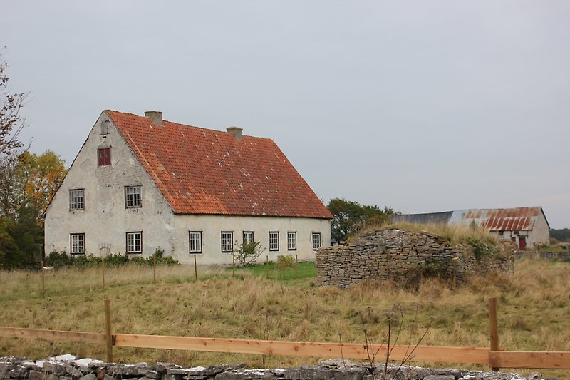 En tvåvåningsvilla med rött tegeltak på landsbygden.