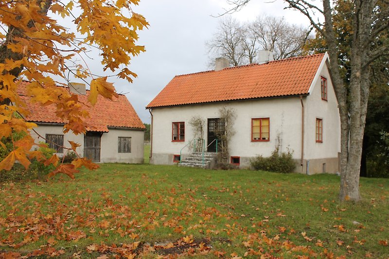 Två små vita hus med röda fönster och röda tak.