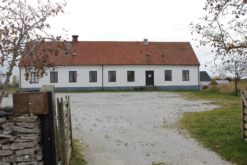 Vit envåningsbyggnad med ett rött tegeltak, svarta fönster och en svart ytterdörr.
