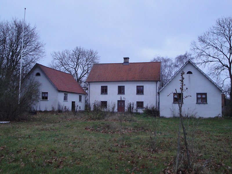 Tre vita byggnader med röda fönster, röda dörrar och röda tegeltak.