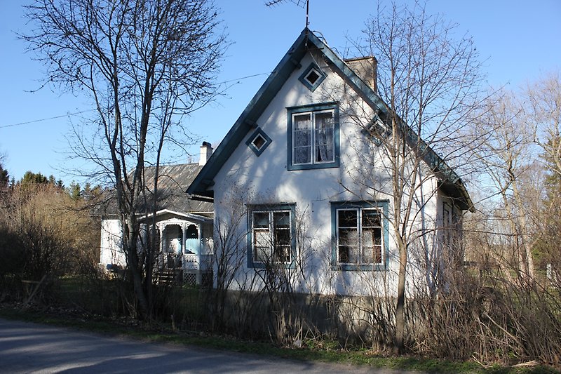 Ett vitt hus med blåa fönsterkarmar, en skorsten och ett svart tak.