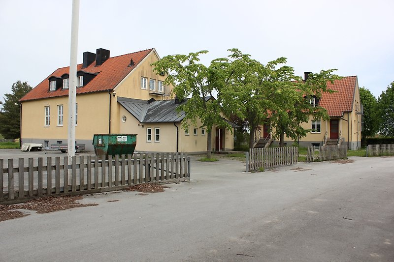 Två gula byggnader med vita fönster, orange tak och svarta skorstenar.