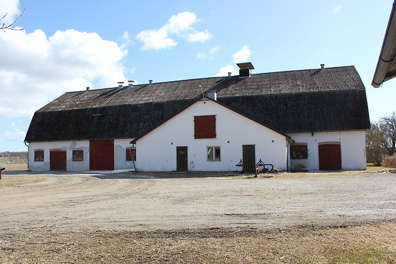 En stor vit lada med ett svart tak