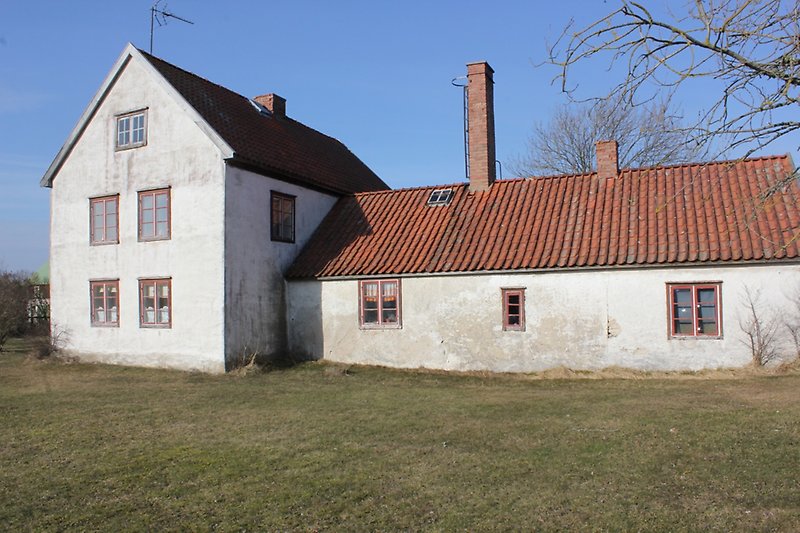 Ett vitt hus med röda fönster, ett rött tegeltak med tre skorstenar.