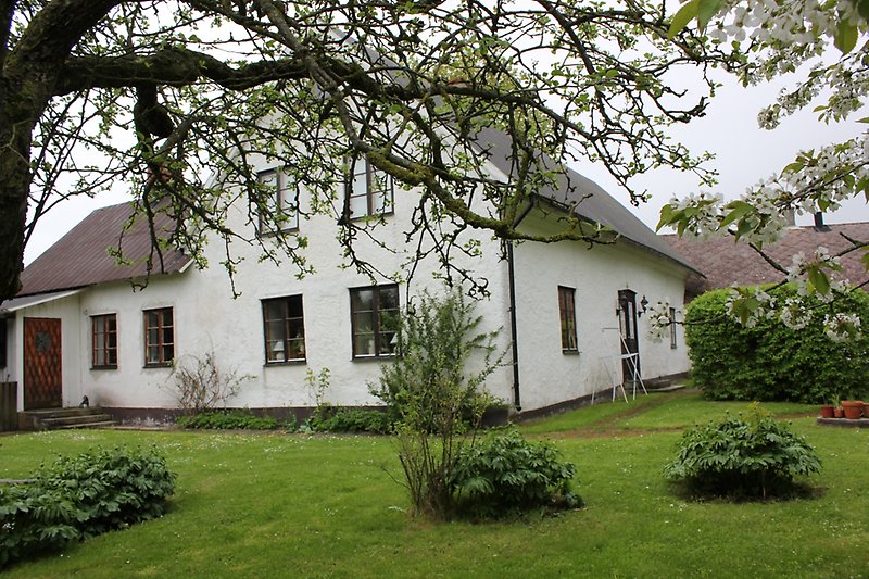 Ett vitt hus med svarta fönster, en svart dörr och svart tak.