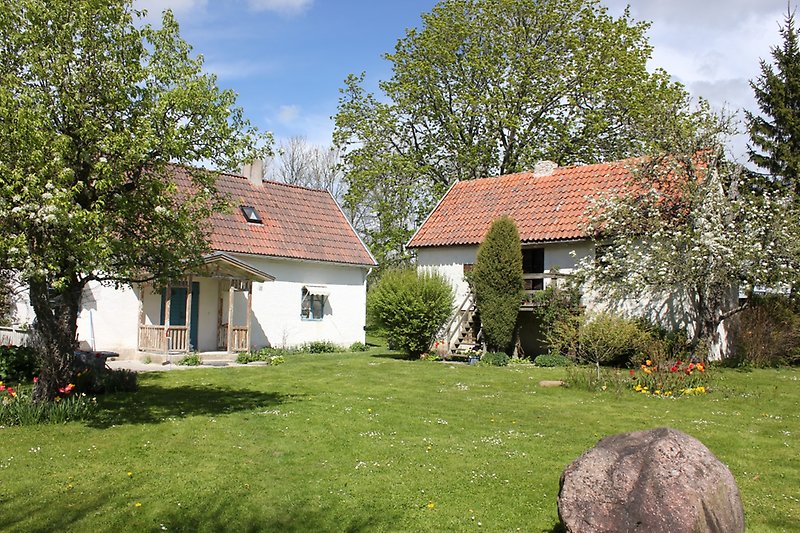 Två små vita hus med blåa dörrar, blåa fönster och röda tegeltak.
