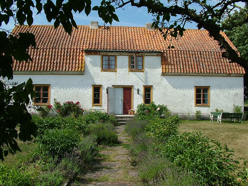 Ett vitt hus med rött tak och ljusbruna fönster.