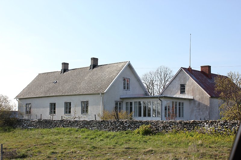 Två gråa hus med skorstenar och en stenmur.