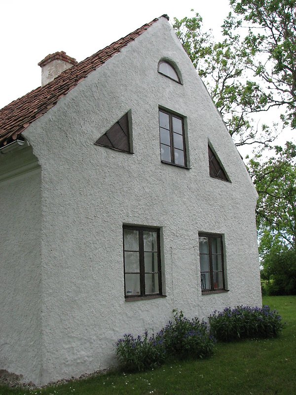 Ett vitt hus med svarta fönster och ett rött tak.