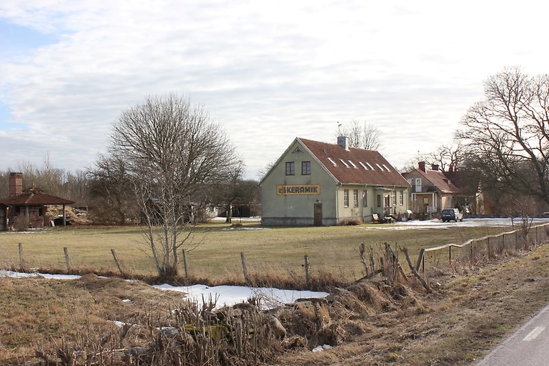En tomt med en stängsel och ett grönt hus.