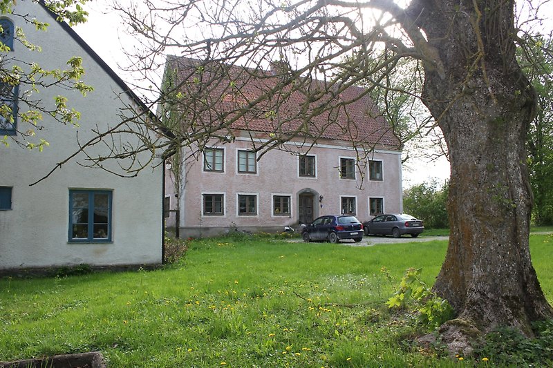 Ett tvåvånings rosa hus med bruna fönster och ett rött tak med en skorsten.