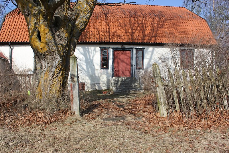 Ett vitt hus med bruna fönster och ett orange tak.
