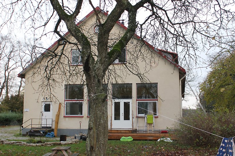 Gaveln på ett beige hus med rödvita fönster, vita dörrar och ett rött plåttak.