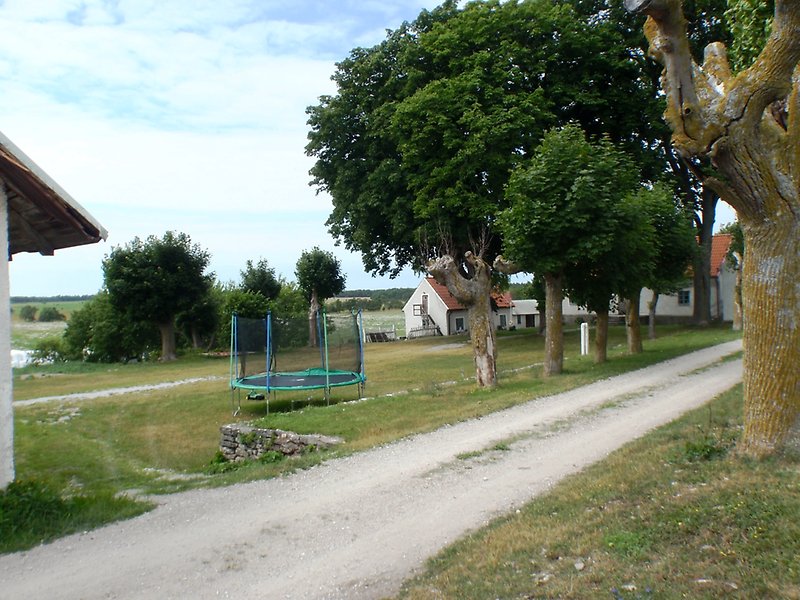 Bebyggelse av flera hus, en studsmatta och en grusväg.